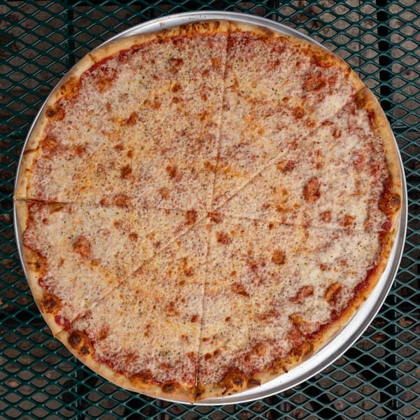 A whole Tommyboy's cheese pizza, cut into slices, on a metal tray over a green mesh table.